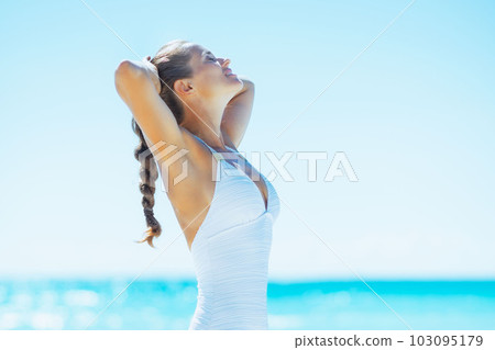 Happy young woman tanning on beach 103095179