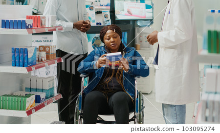 Pharmacy consultant helping client with disability, talking to woman and social worker in pharmaceutical store. Health specialist giving medicine and vitamins to customers, medical center. Pharmacy consultant helping client with disability, talking to woman and social worker in pharmaceutical store. Health specialist giving medicine and vitamins to customers, medical center. 103095274