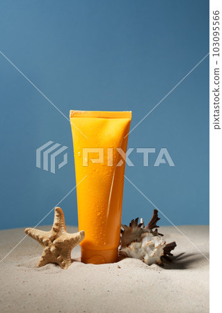Summer sunscreen cream standing on sand with starfish and shell on blue background. Summer sunscreen cream standing on sand with starfish and shell on blue background. 103095566