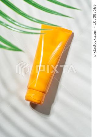 Summer sunscreen cream on sand background with shadow of palm leaf. 103095569