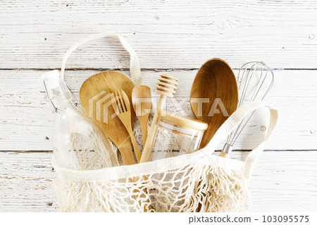 Cotton mesh grocery bag with wooden and glass utensils. Zero waste concept. Cotton mesh grocery bag with wooden and glass utensils. Zero waste concept. 103095575