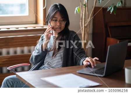 Dark-haired young girl sitting at the laptop and looking involved Dark-haired young girl sitting at the laptop and looking involved 103096256