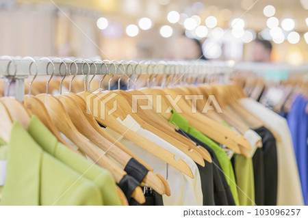 Many wooden hangers on clothes rail close-up. Clothes for sale in shop. Abstract blurred background. Store concept, sale Many wooden hangers on clothes rail close-up. Clothes for sale in shop. Abstract blurred background. Store concept, sale 103096257