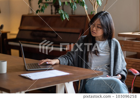 Dark-haired young girl sitting at the laptop and looking involved Dark-haired young girl sitting at the laptop and looking involved 103096258