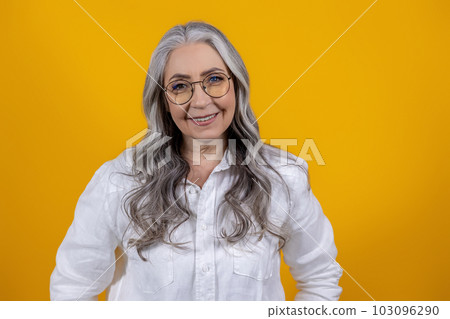 Long-haired beautiful seniort woman standing on yellow background 103096290