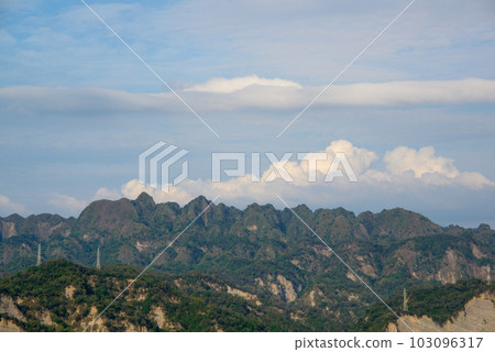 The shape of the mountain is like a flame. Blue sky and moving clouds. The shape of the mountain is like a flame. Blue sky and moving clouds. 103096317