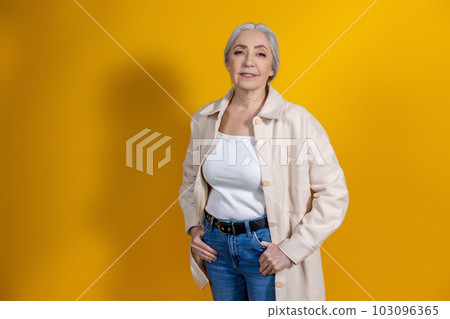 Good-looking woman in beige standing on yellow background 103096365