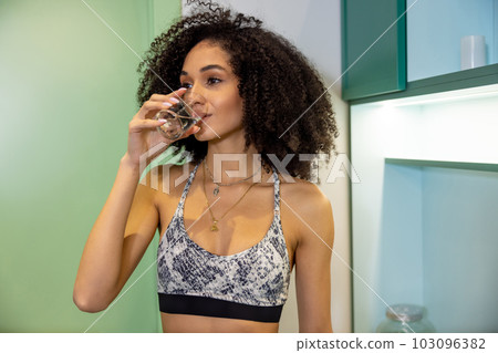 Young woman drinking water after workout in the gym 103096382