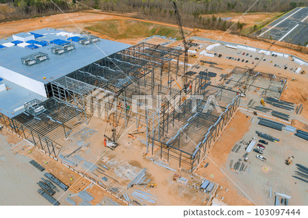 Installing metal frame for steel warehouse construction frame work large cranes in construction site Installing metal frame for steel warehouse construction frame work large cranes in construction site 103097444