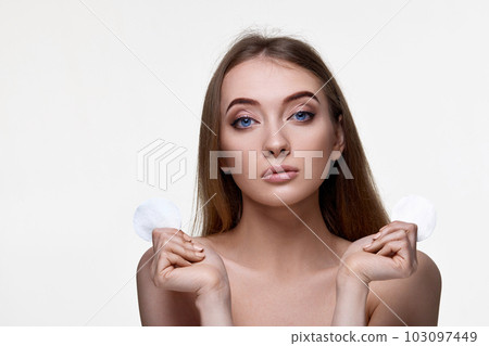woman holding two white cotton disks pad with micellar water woman holding two white cotton disks pad with micellar water 103097449