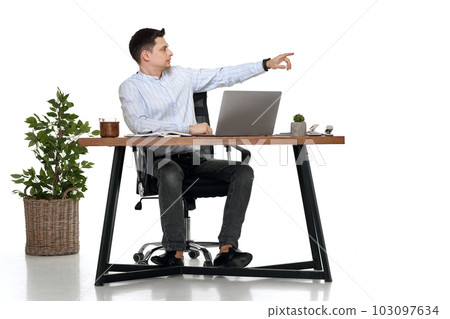 young man using laptop at table and pointing at copy space 103097634