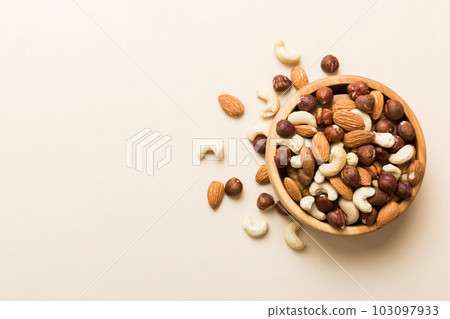 Assortment of nuts in wooden bowl on colored table. Cashew, hazelnuts, walnuts, almonds. Mix of nuts Top view with copy space Assortment of nuts in wooden bowl on colored table. Cashew, hazelnuts, walnuts, almonds. Mix of nuts Top view with copy space 103097933