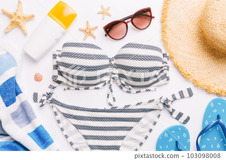 Woman swimwear and beach accessories flat lay top view on colored background Summer travel concept. bikini swimsuit, straw hat and seasheels. Copy space Top view 103098008