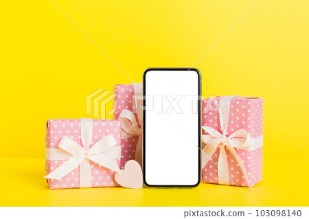 mobile phone with blank screen on colored background with hearts, calendar and gift box, valentine day concept perspertive view flat lay mobile phone with blank screen on colored background with hearts, calendar and gift box, valentine day concept perspertive view flat lay 103098140