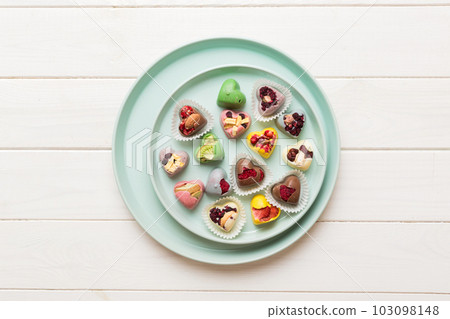 Plate with different chocolate on colored background. Assortment of fine chocolates top view vith copy space Health and obesity concept Plate with different chocolate on colored background. Assortment of fine chocolates top view vith copy space Health and obesity concept 103098148