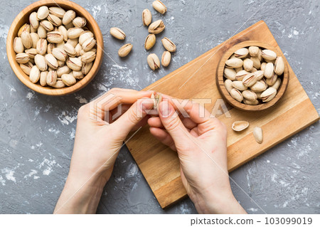 Woman hands holding a wooden bowl with pistachios nuts. Healthy food and snack. Vegetarian snacks of different nuts Woman hands holding a wooden bowl with pistachios nuts. Healthy food and snack. Vegetarian snacks of different nuts 103099019
