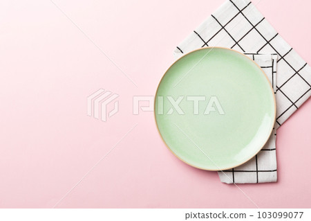 Top view on colored background empty round green plate on tablecloth for food. Empty dish on napkin with space for your design Top view on colored background empty round green plate on tablecloth for food. Empty dish on napkin with space for your design 103099077