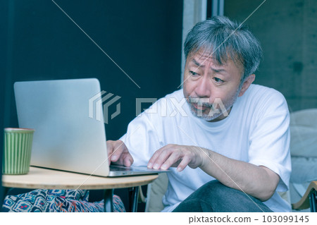 A middle-aged man with a troubled face working on a computer A middle-aged man with a troubled face working on a computer 103099145