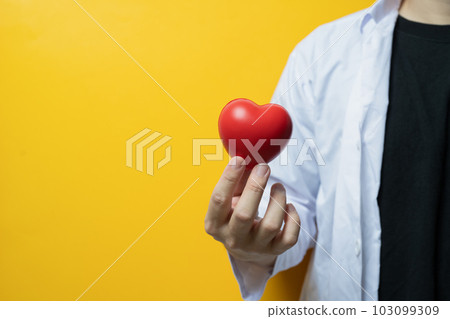 Doctor hand holding red heart on yellow background Cardiology, medicine, donation and healthcare concept 103099309