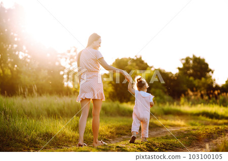 Mother and daughter playing together in summer park at sunset. Happy mom with small child having fun Mother and daughter playing together in summer park at sunset. Happy mom with small child having fun 103100105