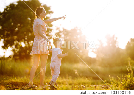 Mother and daughter playing together in summer park at sunset. Happy mom with small child having fun 103100106