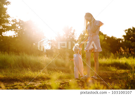 Mother and daughter playing together in summer park at sunset. Happy mom with small child having fun Mother and daughter playing together in summer park at sunset. Happy mom with small child having fun 103100107