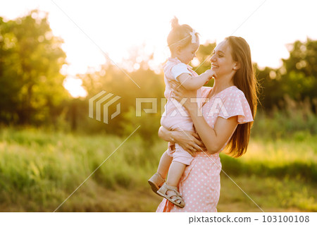 Mother and daughter playing together in summer park at sunset. Happy mom with small child having fun Mother and daughter playing together in summer park at sunset. Happy mom with small child having fun 103100108