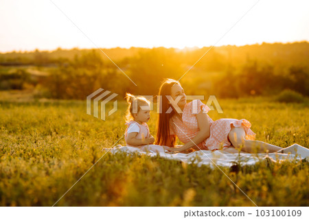 Mother and little daughter playing together in summer sunset. Happy mom with small child having fun. Mother and little daughter playing together in summer sunset. Happy mom with small child having fun. 103100109