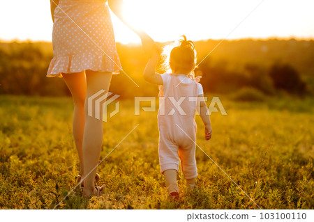 Mother and little daughter playing together in summer sunset. Happy mom with small child having fun. 103100110