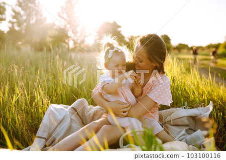 Mother and daughter playing together in summer park at sunset. Happy mom with small child having fun Mother and daughter playing together in summer park at sunset. Happy mom with small child having fun 103100116