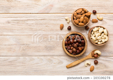 Assortment of nuts in wooden bowl on colored table. Cashew, hazelnuts, walnuts, almonds. Mix of nuts Top view with copy space Assortment of nuts in wooden bowl on colored table. Cashew, hazelnuts, walnuts, almonds. Mix of nuts Top view with copy space 103100278