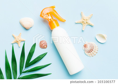 Sunscreen spray bottle. Bottle with sun protection cream and sea shells with tropical green leaf on color background, top view Sunscreen spray bottle. Bottle with sun protection cream and sea shells with tropical green leaf on color background, top view 103100377