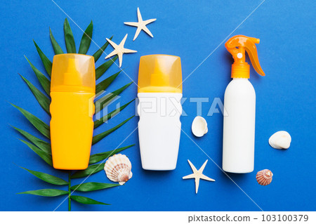 Sunscreen spray bottle. Bottle with sun protection cream and sea shells with tropical green leaf on color background, top view Sunscreen spray bottle. Bottle with sun protection cream and sea shells with tropical green leaf on color background, top view 103100379