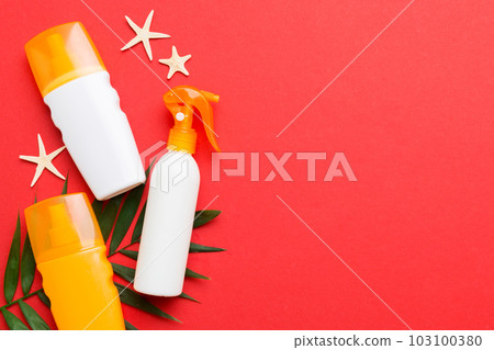 Sunscreen spray bottle. Bottle with sun protection cream and sea shells with tropical green leaf on color background, top view Sunscreen spray bottle. Bottle with sun protection cream and sea shells with tropical green leaf on color background, top view 103100380
