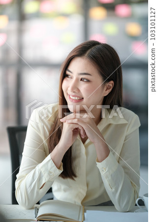 Charming Asian woman with a smile looking out to the window in the office. 103101127