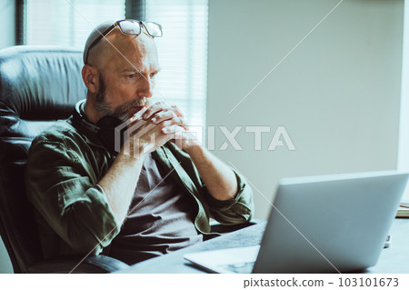 Middle-aged man fully focused on work he looks intently at computer on table. Deep in thought, he reflects on task or problem at hand, demonstrating his analytical and strategic thinking skills Middle-aged man fully focused on work he looks intently at computer on table. Deep in thought, he reflects on task or problem at hand, demonstrating his analytical and strategic thinking skills 103101673