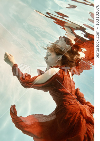 Portrait of a woman in a red dress floating underwater Portrait of a woman in a red dress floating underwater 103102076