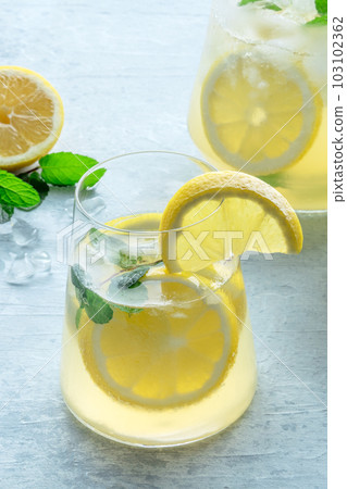 Lemonade with mint. Lemon water drink with ice. A glass and a pitcher 103102362