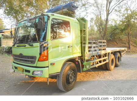 Green colored flatbed heavy trucks used to transport and distribute cements sacks from factory to points of sales or distributors networks shops around Asia  103102666