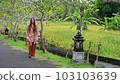 beautiful young woman walks through a tropical park, a religious place in indonesia 103103639