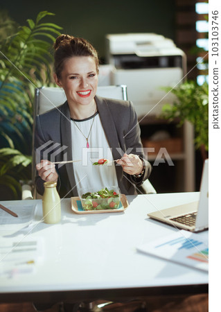 smiling business woman in green office eating salad smiling business woman in green office eating salad 103103746