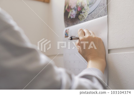 woman writing appointments on calendar 103104374