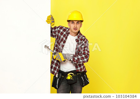 professional builder in work clothes in helmet holding hammer. professional builder in work clothes in helmet holding hammer. 103104384