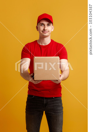 Delivery man employee in red cap, t-shirt holding cardboard box Delivery man employee in red cap, t-shirt holding cardboard box 103104387