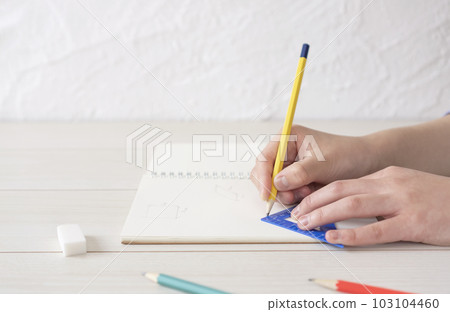 Child writing shapes in notebook. math problem solver 103104460