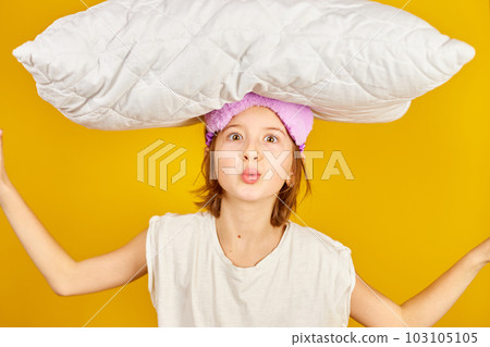 Funny teenage girl in white pyjamas with a violet sleeping mask hold pillow Funny teenage girl in white pyjamas with a violet sleeping mask hold pillow 103105105