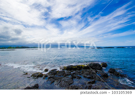 遠處的莫納克亞山從夏威夷大島的黑沙海岸俯瞰大海。 遠處的莫納克亞山從夏威夷大島的黑沙海岸俯瞰大海。 103105369