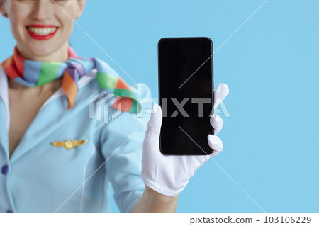 Female air hostess on blue showing smartphone blank screen 103106229