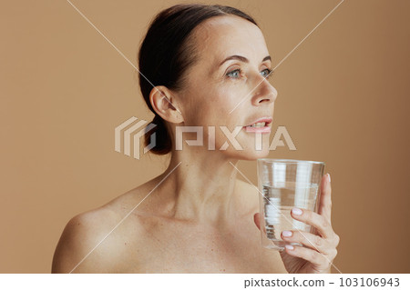 modern 40 years old woman with glass of water isolated on beige modern 40 years old woman with glass of water isolated on beige 103106943