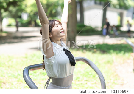 在新鮮的綠色公園裡伸展身體的年輕女人 在新鮮的綠色公園裡伸展身體的年輕女人 103106971